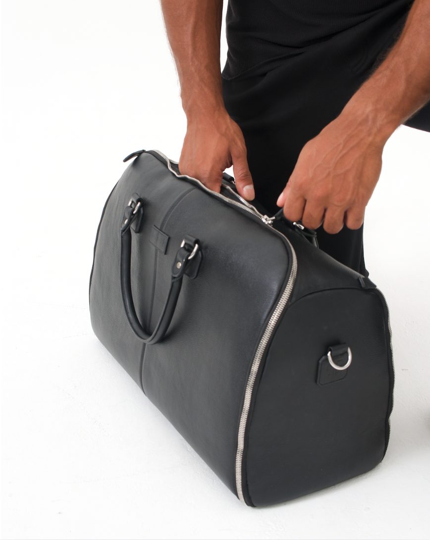 The leather weekender held by the handles