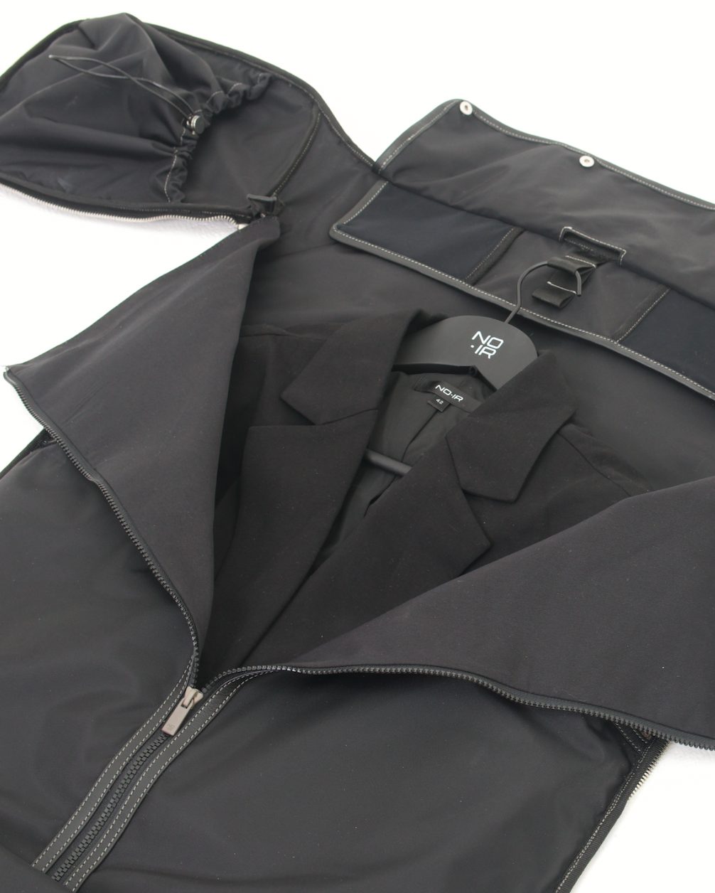 The garment bag laid flat with a tailored blazer on a branded hanger
