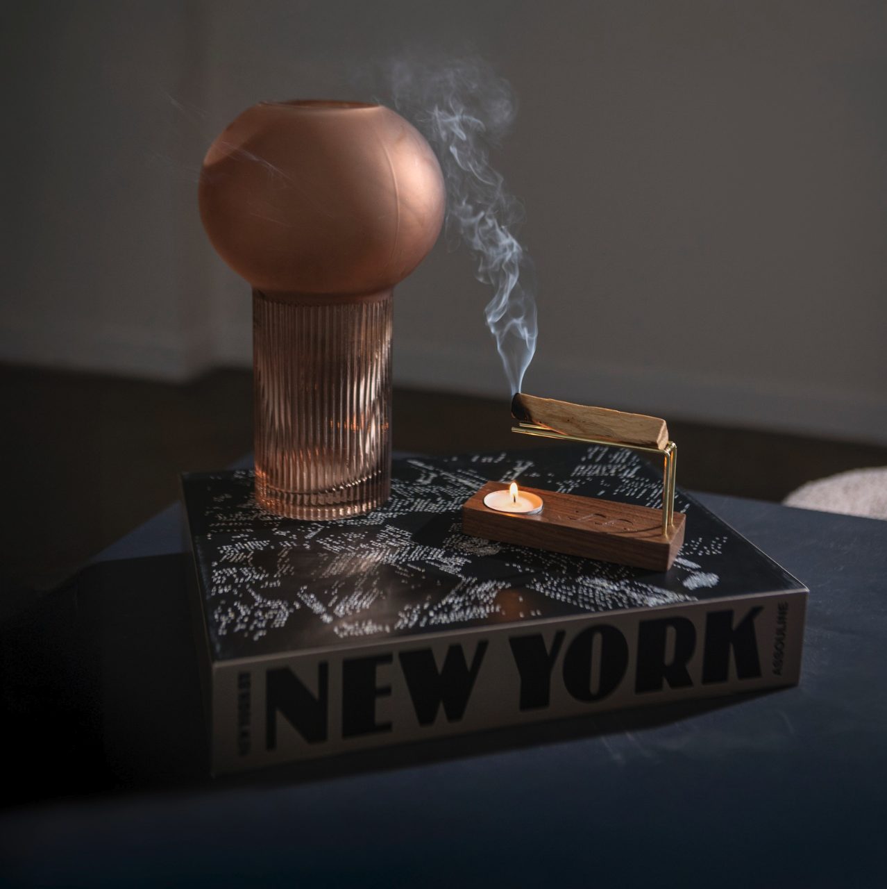 Palo santo burning on the walnut base in low afternoon light