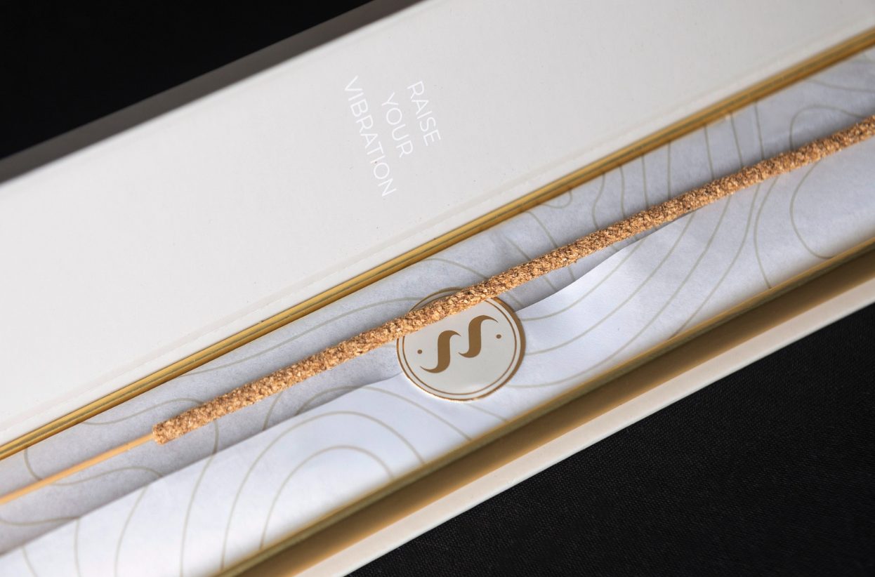 Incense box opened, Raise Your Vibration printed inside over patterned tissue and a gold seal